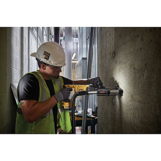 Rotary hammer with dust extractor telescope being used by person