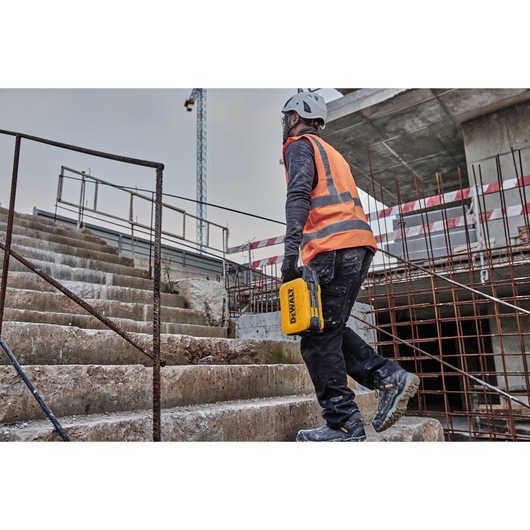 Powershift 554WH battery being carried by a construction worker walking up concrete steps