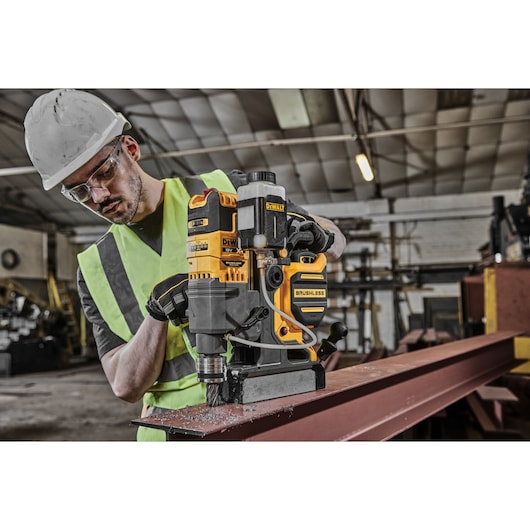 A TRADESMAN USING A DCD1623 TO CUT A HOLE IN A STEEL BEAM