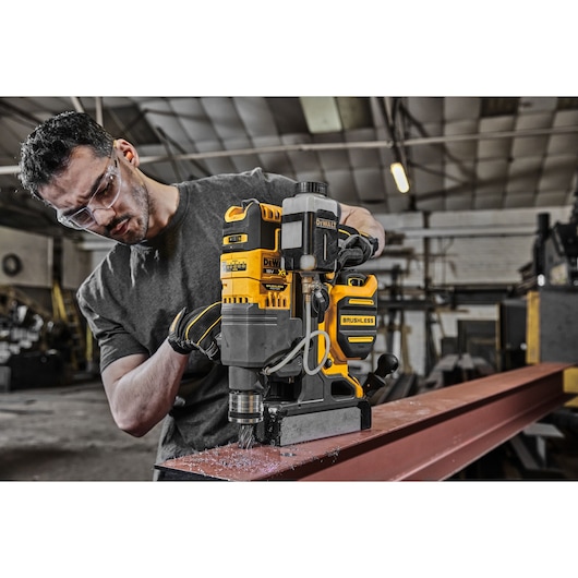 A TRADESMAN USING A DCD1623 TO CUT A HOLE IN A STEEL BEAM