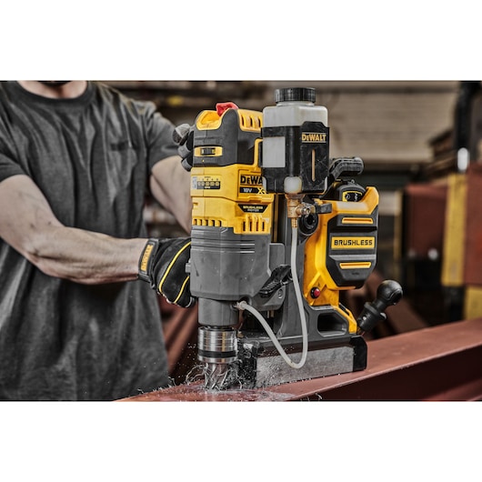 A TRADESMAN USING A DCD1623 TO CUT A HOLE IN A STEEL BEAM