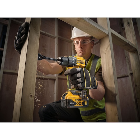 18V XR Brushless Compact Hammer Drill Driver with 18V 5Ah battery used by worker to drill wooden frame