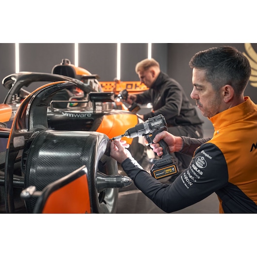 McLaren mechanic using DEWALT/McLaren drill driver on McLaren racing car