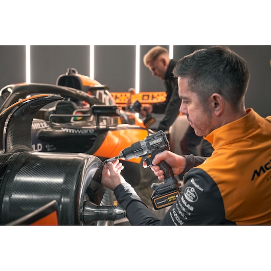 McLaren mechanic using DEWALT/McLaren drill driver on McLaren racing car