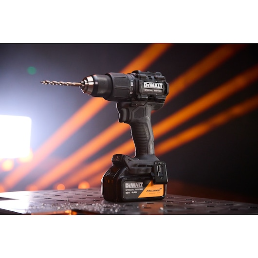 DEWALT x McLaren F1 Team 18V XR Special Edition Hammer Drill Driver with 4Ah battery standing on a metal sheet with holes