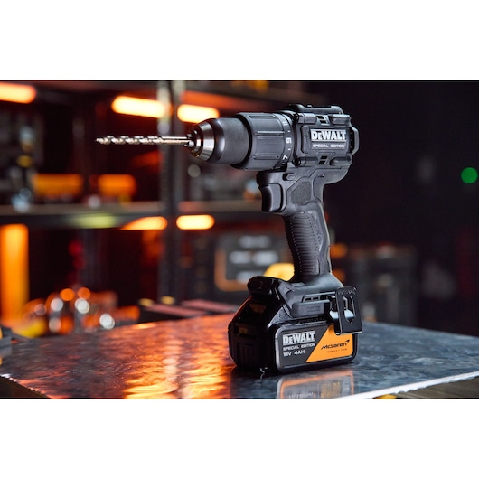 DEWALT x McLaren F1 Team 18V XR Special Edition Hammer Drill Driver with 4Ah battery standing on a metal sheet