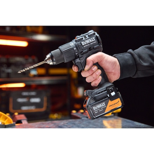 A hand holds the DEWALT x McLaren F1 Team 18V XR Special Edition Hammer Drill Driver with 4Ah battery