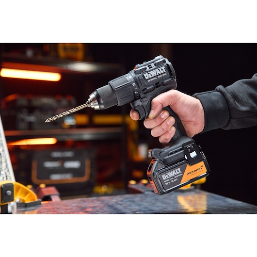 A hand holds the DEWALT x McLaren F1 Team 18V XR Special Edition Hammer Drill Driver with 5Ah battery