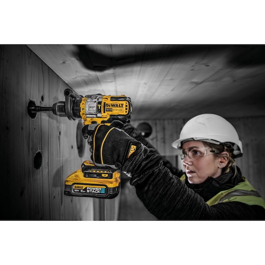 18V XR Brushless drill driver with Powerstack battery cutting hole into wooden wall