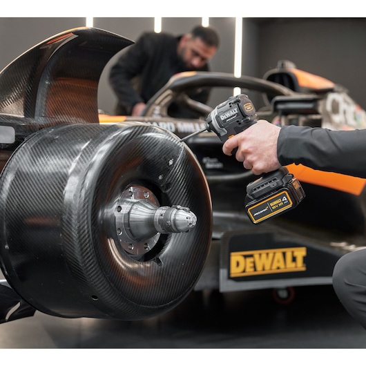 McLaren mechanic using DEWALT/McLaren impact driver on McLaren racing car
