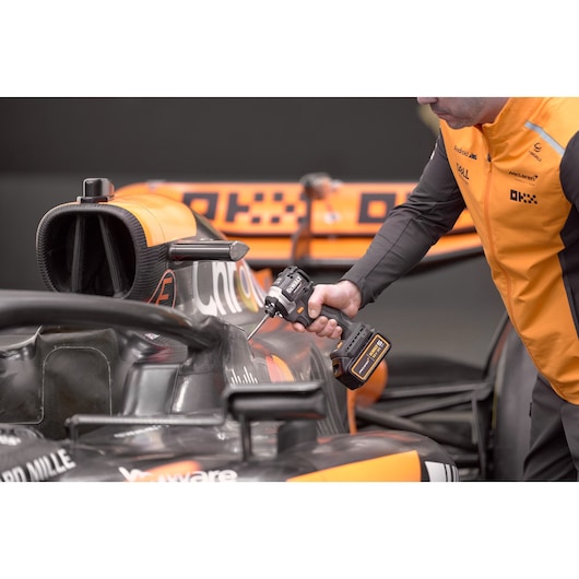 McLaren mechanic using DEWALT/McLaren impact driver on McLaren racing car