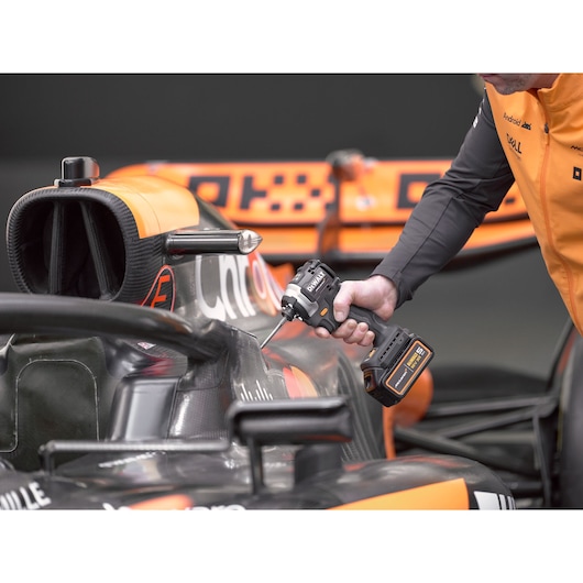 McLaren mechanic using DEWALT/McLaren impact driver on McLaren racing car