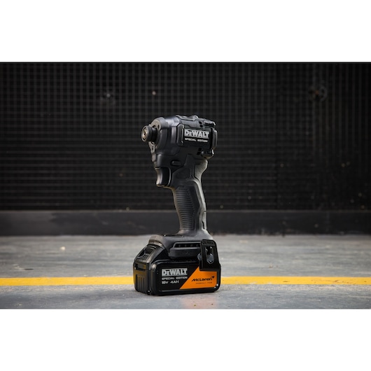 DEWALT x McLaren F1 Team 18V XR Special Edition Impact Driver with 4Ah battery standing on a concrete floor