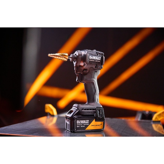DEWALT x McLaren F1 Team 18V XR Special Edition Impact Driver with 5Ah battery standing on a metal sheet