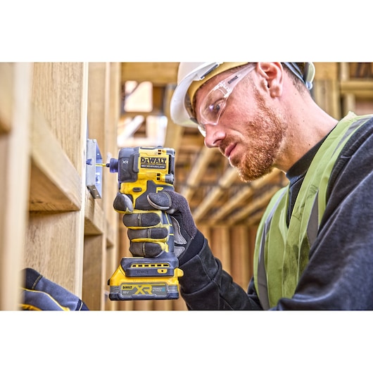 Worker attaching a metal back box onto a wooden frame using  DCF870 18V XR Brushless impact driver