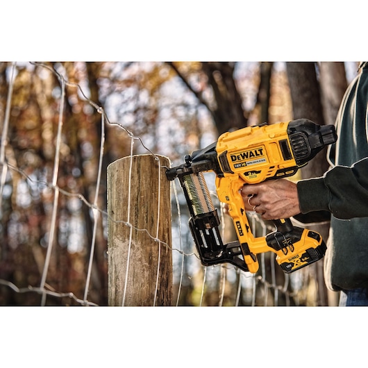 CORDLESS FENCING STAPLER being used on a wooden post