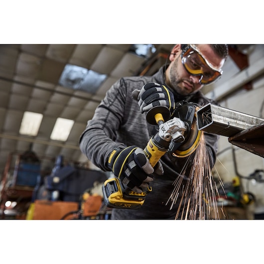 Worker uses the DEWALT 18V XR Compact 125mm Angle Grinder to cut steel square tubing