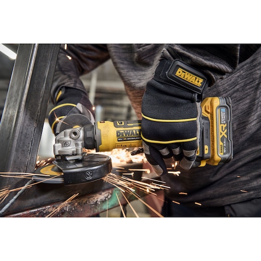 Worker uses the DEWALT 18V XR Compact 125mm Angle Grinder to grind steel square tubing