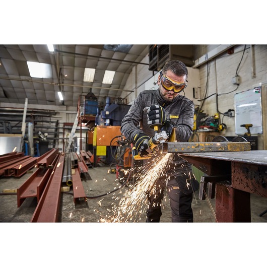 Worker uses the DEWALT 18V XR Compact 125mm Angle Grinder with 3.5ah battery  to cut steel square tubing