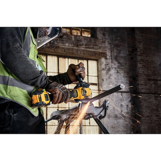 Brushless 18V XR 125mm cordless angle grinder being used to cut rebar in a workshop setting