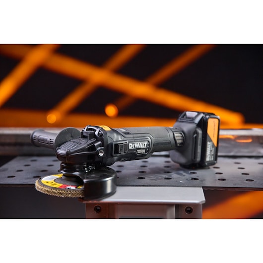 DEWALT x McLaren F1 Team 18V XR Special Edition Grinder with 5Ah battery sitting on a metal sheet