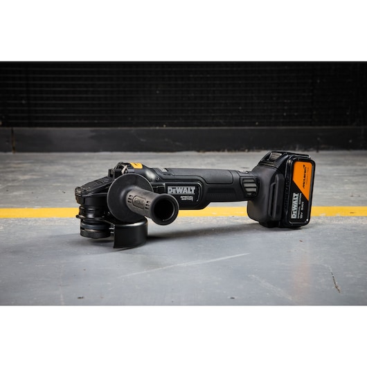 DEWALT x McLaren F1 Team 18V XR Special Edition Grinder with 5Ah battery sitting on a concrete floor