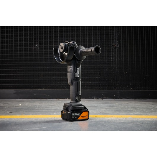DEWALT x McLaren F1 Team 18V XR Special Edition Grinder with 5Ah battery standing vertically on a concrete floor