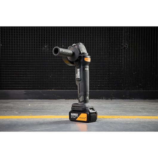 DEWALT x McLaren F1 Team 18V XR Special Edition Grinder with 5Ah battery standing vertically on a concrete floor