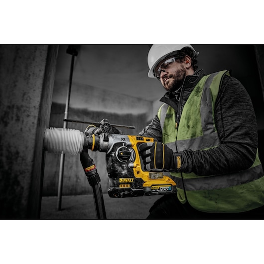 18V XR Brushless SDS-Plus Hammer Drill drilling into concrete wall using a dust extractor.