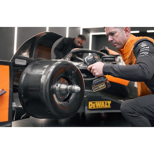 McLaren mechanic using DEWALT/McLaren drill driver on McLaren racing car