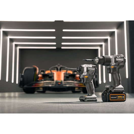 DEWALT/McLaren drill driver stands in the foreground with a McLaren racing car in the background