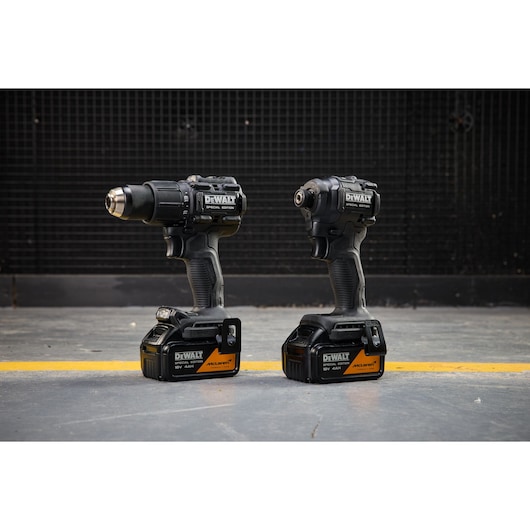 DEWALT x McLaren F1 Team 18V XR Special Edition Hammer Drill Driver and Compact Impact Driver with 4Ah batteries standing on a concrete floor