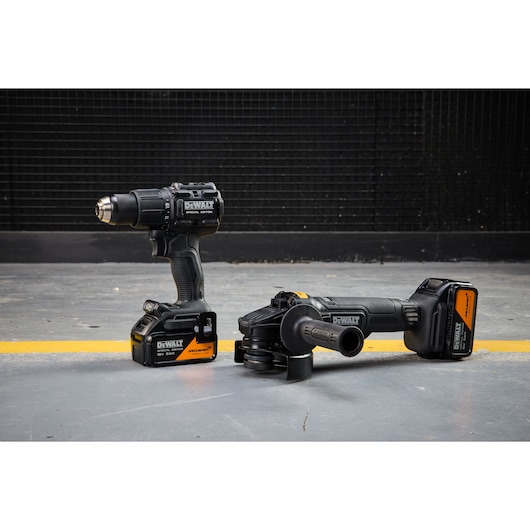 DEWALT x McLaren F1 Team 18V XR Special Edition Hammer Drill Driver and Grinder with 5Ah batteries standing on a concrete floor