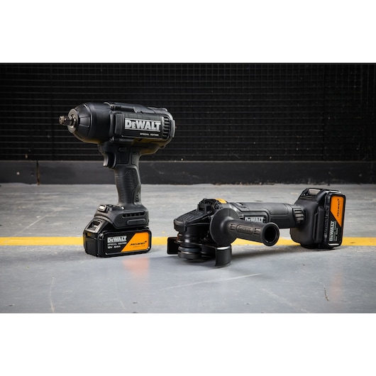 DEWALT x McLaren F1 Team 18V XR Special Edition Impact Wrench and Grinder with 5Ah batteries standing on a concrete floor