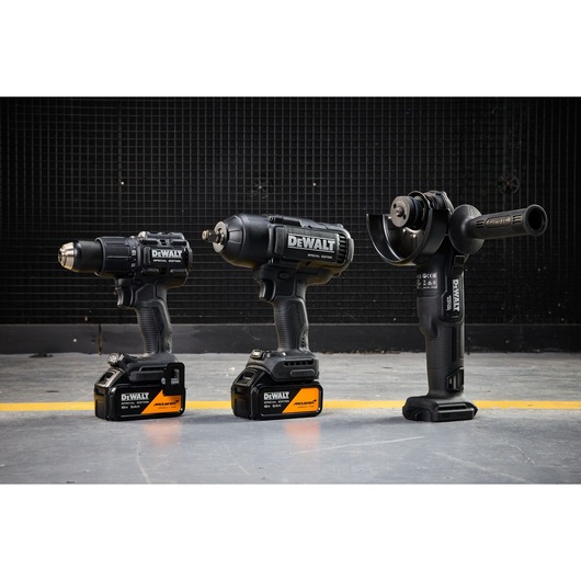 DEWALT x McLaren F1 Team 18V XR Special Edition Hammer Drill Driver, Impact Wrench and Griinder with 5Ah batteries standing on a concrete floor