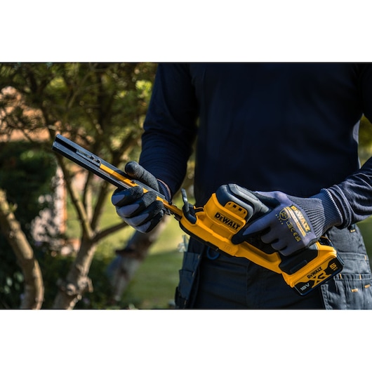 Blade guard being removed from the DEWALT 18V XR Compact Hedge Trimmer 