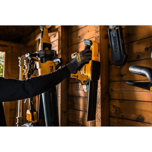 The DEWALT 18V XR Compact Hedge Trimmer being hung on a shed wall 