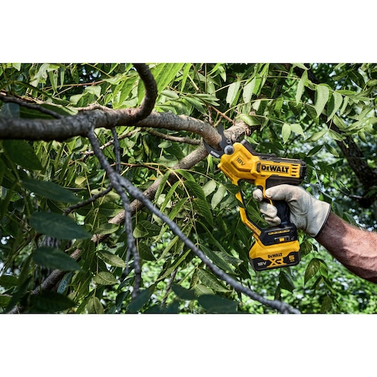 User trimming leaves using powered cordless pruner