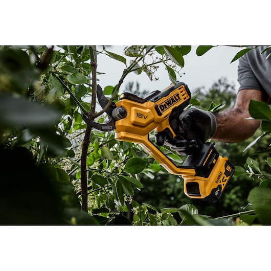 User trimming branch using powered cordless pruner