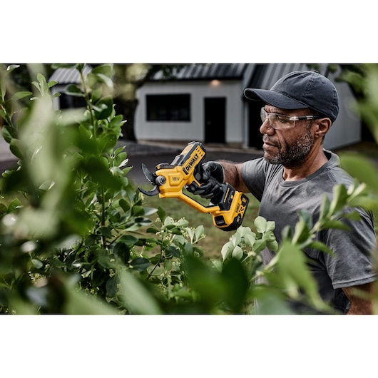 User trimming leaves using powered cordless pruner