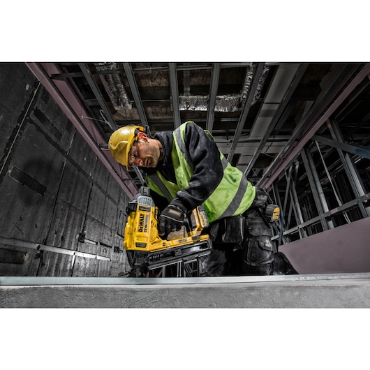 Overhead view of  Cordless Concrete Nailer being used by a person to install drywall track.
