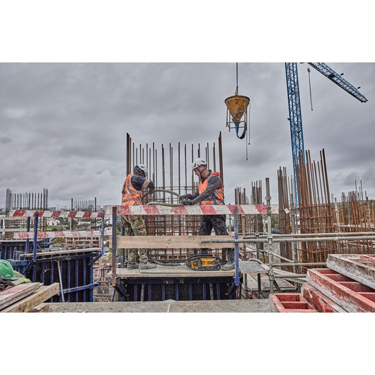 Two construction workers use Powershift Powerpack Concrete Vibrator and hose to pour concrete into a rebar column