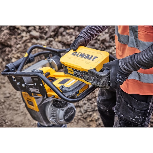 Construction workers holds a Powershift Battery DCBPS0554 next to a Powershift Rammer on a construction site