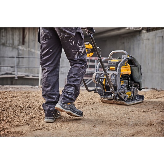 Cropped view of a construction worker using Powershift Plate Compactor. Worker's legs and compactor are in view.