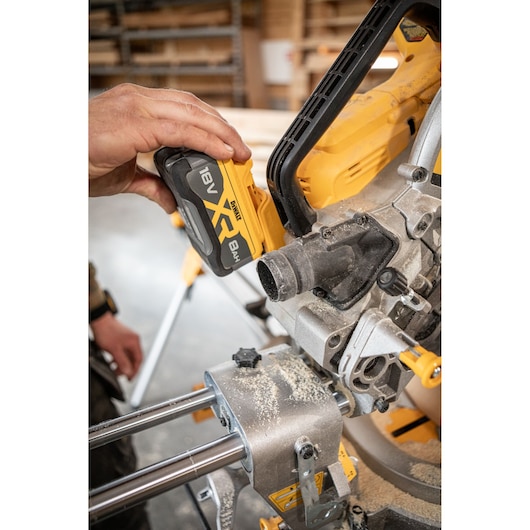 Carpenter adding 8Ah battery to the DEWALT 18V XR 305mm Slide Mitre Saw in wood shop