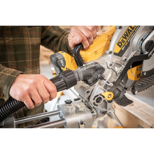 Carpenter attaching nozzle to the DEWALT 18V XR 305mm Slide Mitre Saw in wood shop