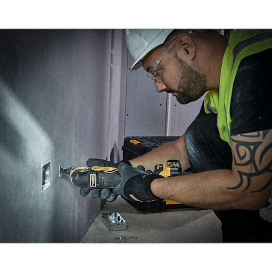 Multi tool being used to cut into plasterboard