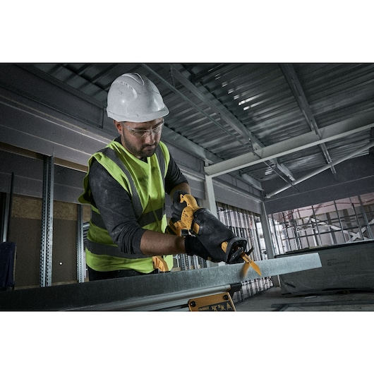 Workman using a reciprocating saw to cut metal