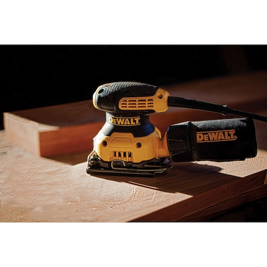 One quarter inch sheet palm grip sander placed on top of a wooden sheet.