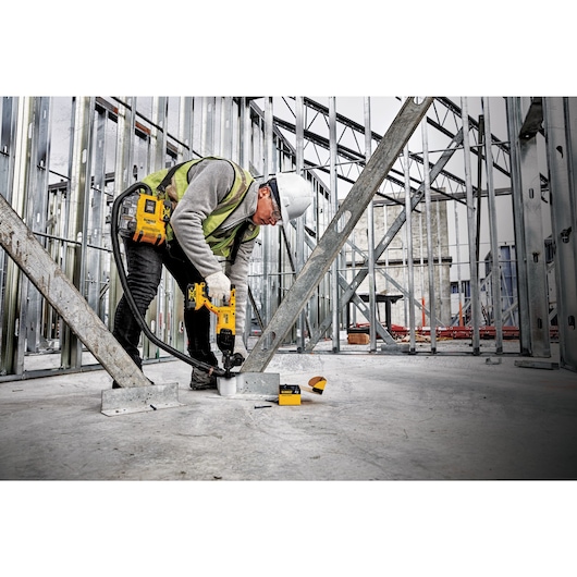 Brushless universal dust extractor being used by a person to cut out drywall.